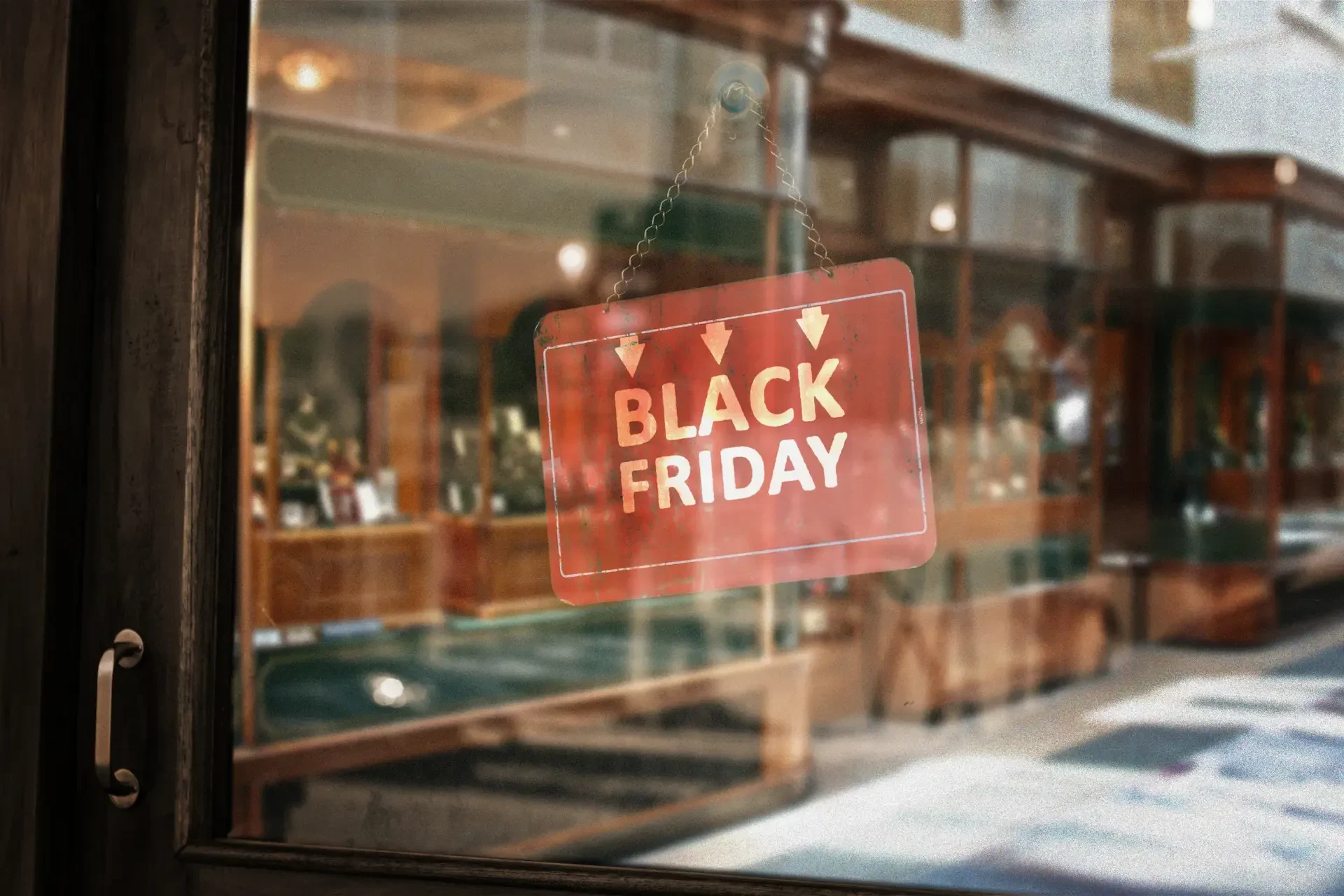 A red "black friday" sign hangs on the glass door of a shop, hinting at business preparation for the festive season, with the store's interior and reflections visible in the background.