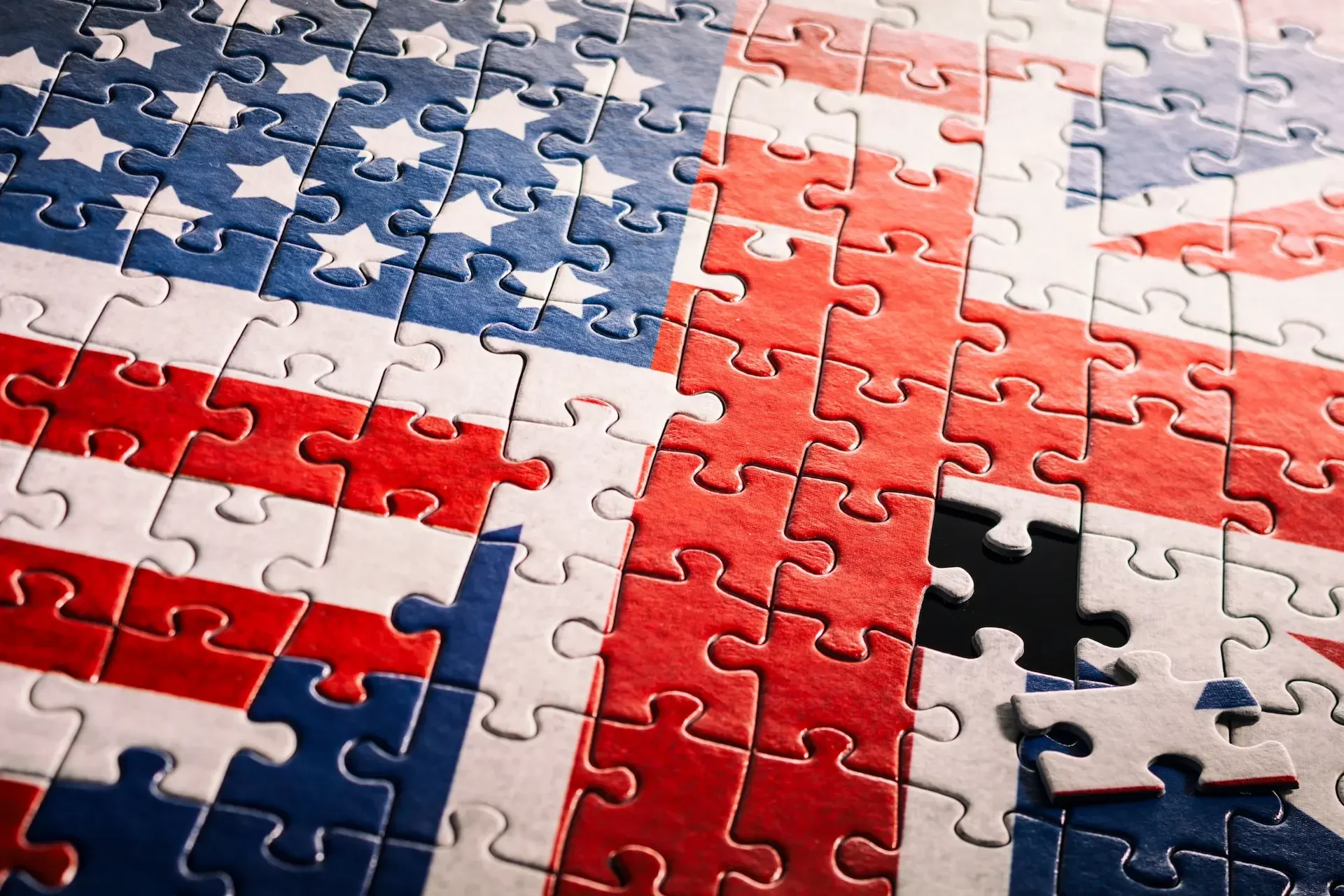 A jigsaw puzzle combining the flags of the united states and the united kingdom, with one piece missing near the lower right corner, symbolizes the evolving uk ai landscape and growing us tech investment.