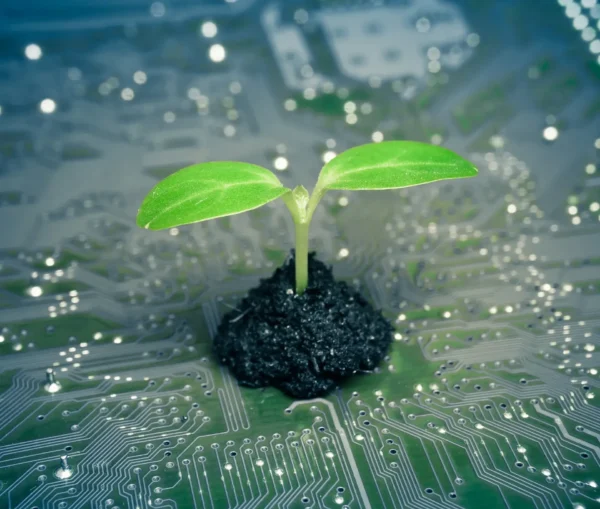 A green seedling growing from a small pile of soil placed on top of an electronic circuit board, symbolizing sustainable growth through green tech innovation.
