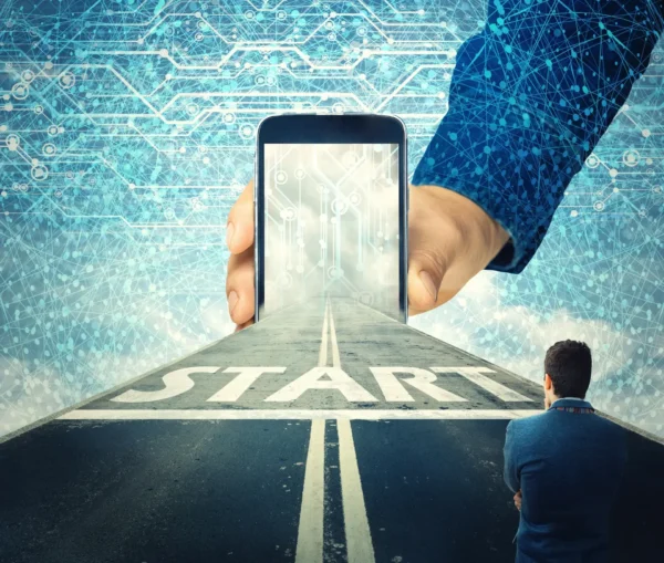 A person stands at the start of a road leading into a giant smartphone held by a hand, symbolizing a digital journey, it roadmap, or new technological beginning.