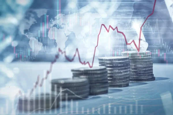 Stacks of coins are shown in the foreground with red and blue financial graphs and a faint world map overlay in the background, illustrating investor ready global financial markets and the growing role of cyber security.