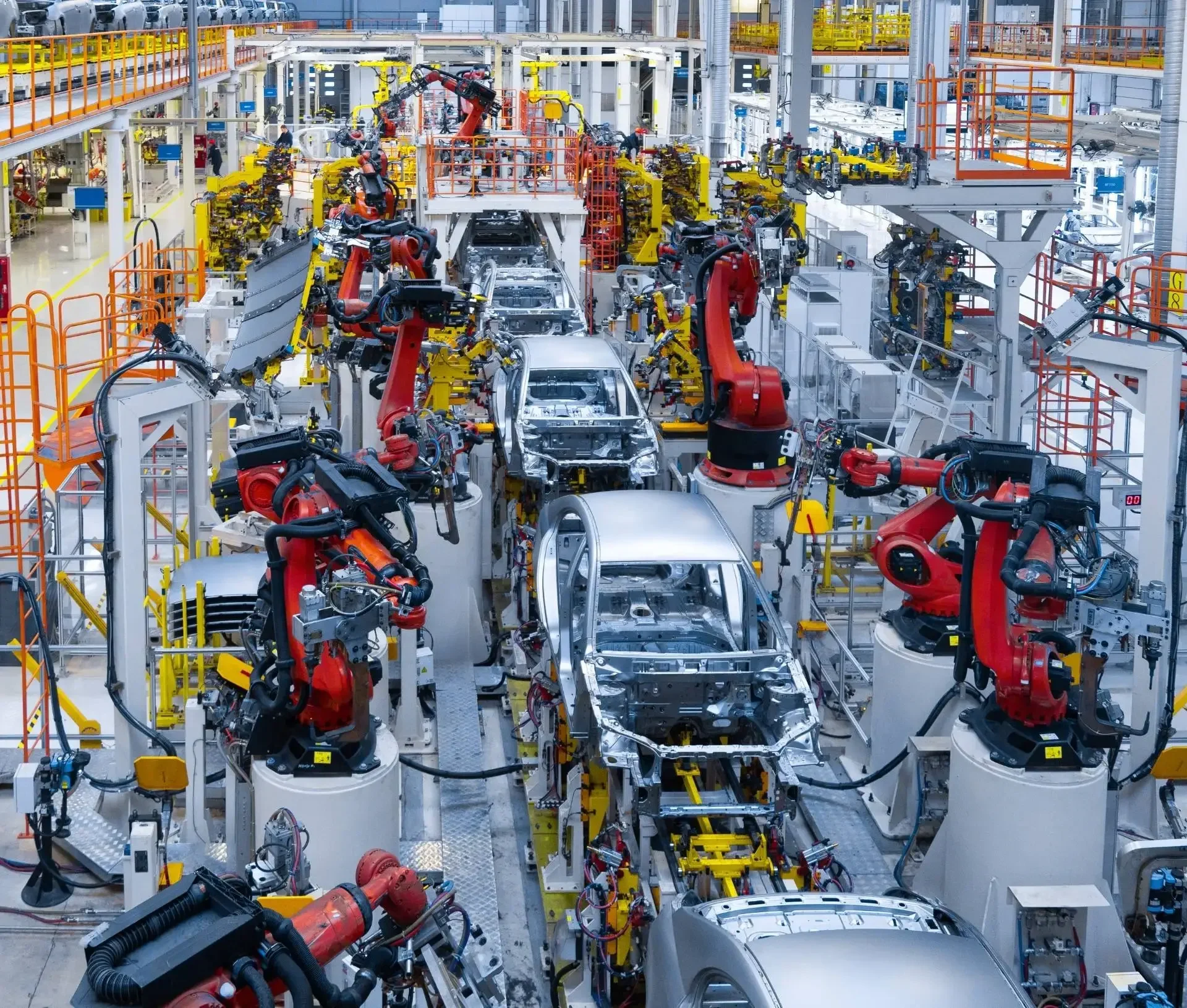 Robotic arms assemble cars on an automated production line in a large, brightly lit automotive factory, showcasing cyber resilience as uk businesses like jaguar land rover strengthen defenses against potential cyber attacks.