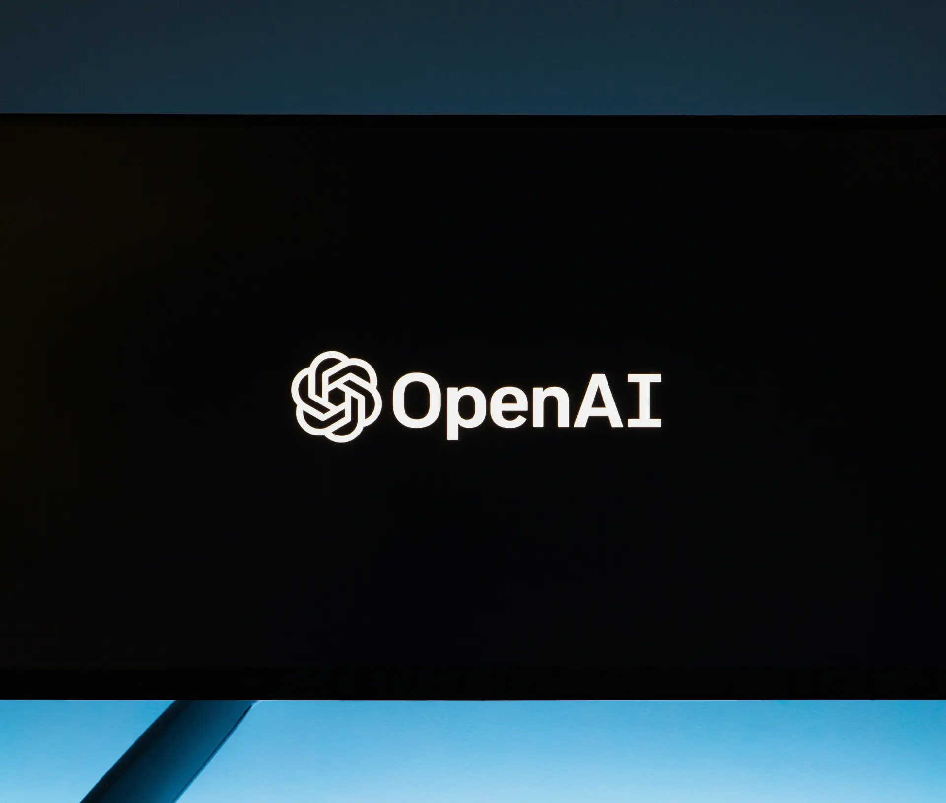 A black screen displays the white OpenAI logo and the word “OpenAI” in the centre, evoking a sense of advanced AI training at work.