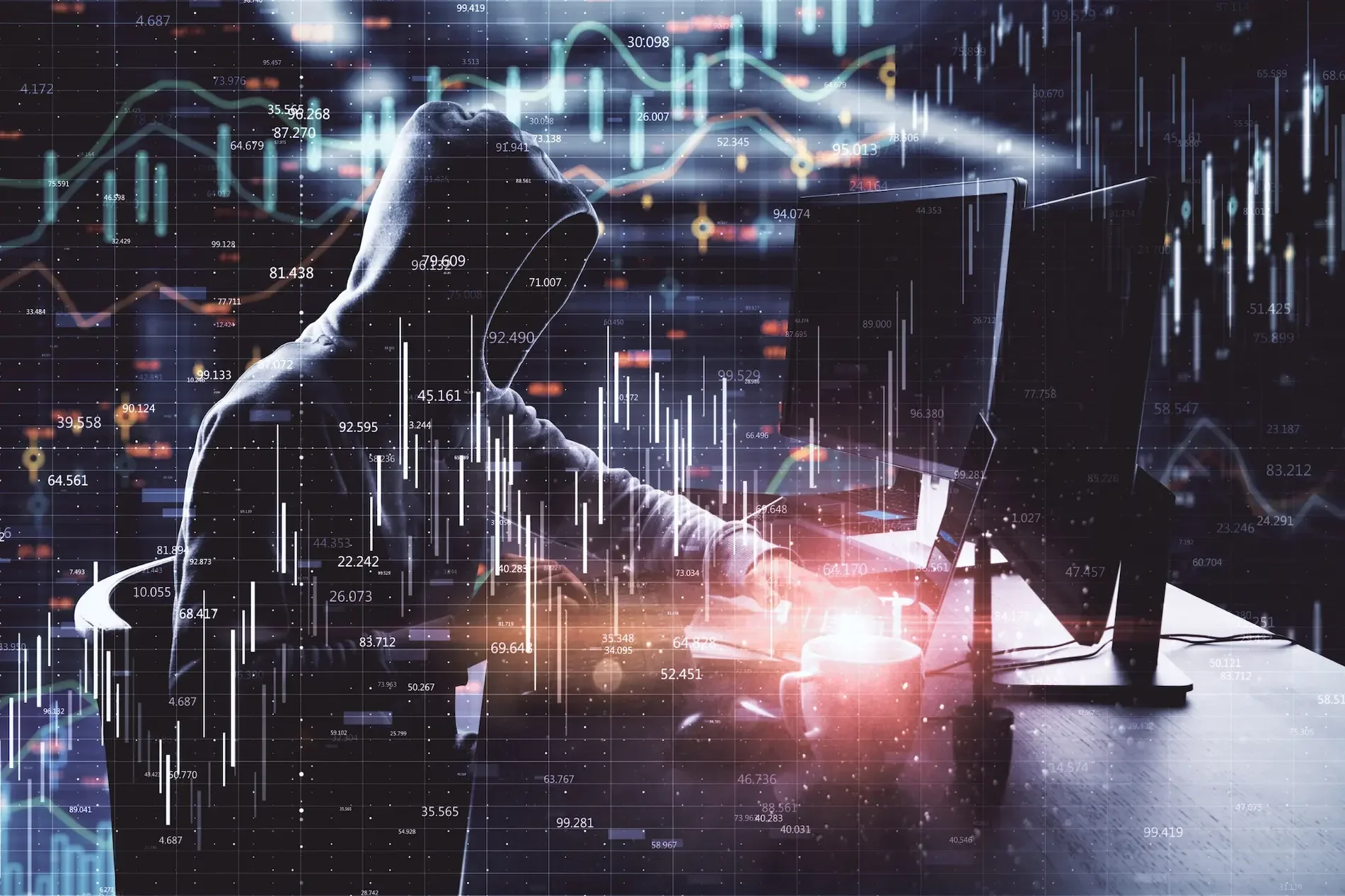 A person in a hoodie uses a computer in a dark room, with digital financial graphs and data overlays in the foreground, highlighting workplace security risks like phishing emails.
