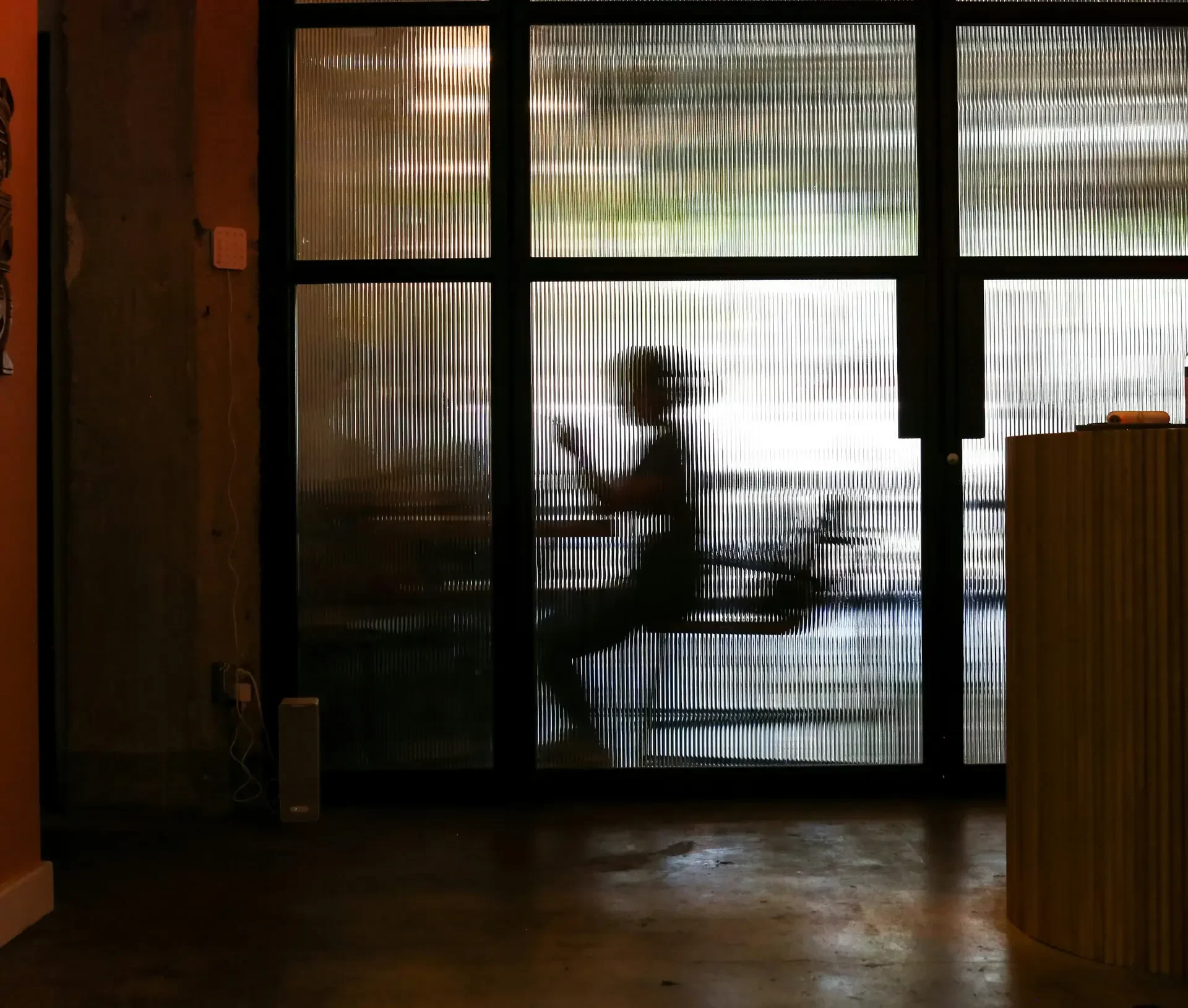 A silhouette of a person riding a bicycle is visible through a translucent glass wall inside a building, symbolizing the steady movement and resilience essential for smes focused on business continuity planning.