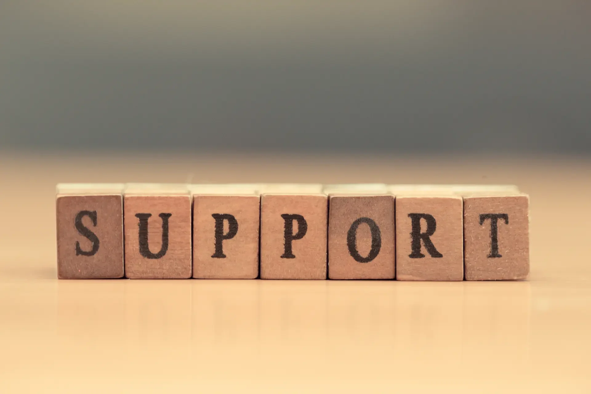 Wooden blocks arranged in a row spell out the word "support" against a neutral background, symbolizing the foundation of reliable it support.