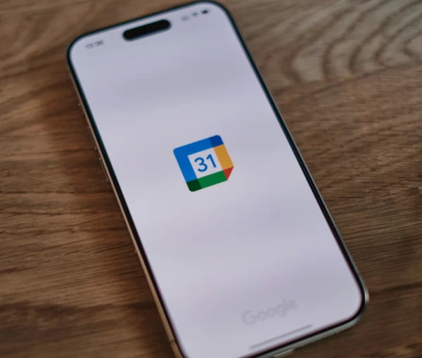 A smartphone screen displaying the Google Calendar app icon on a wooden surface.