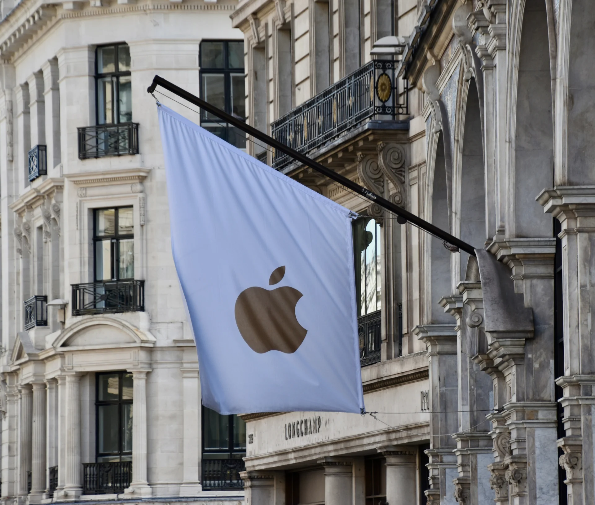 A white flag with a gold Apple logo hangs from an ornate building façade during the October 2026 Pro and Tell event.