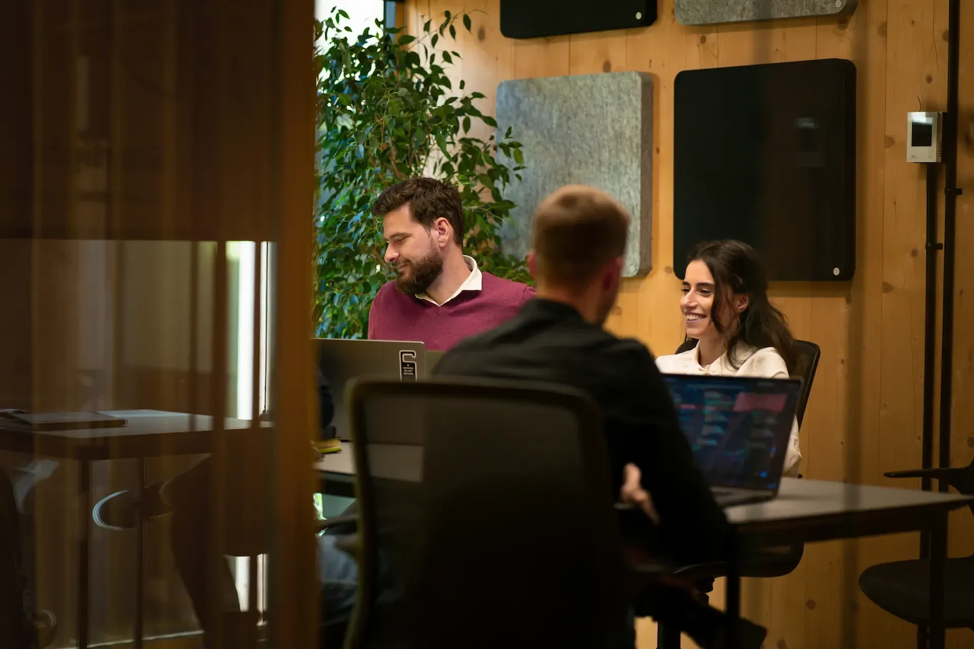 Three people sit at a table with laptops in a modern office space, engaged in conversation about quarterly business reviews and collaborating with their virtual cio.