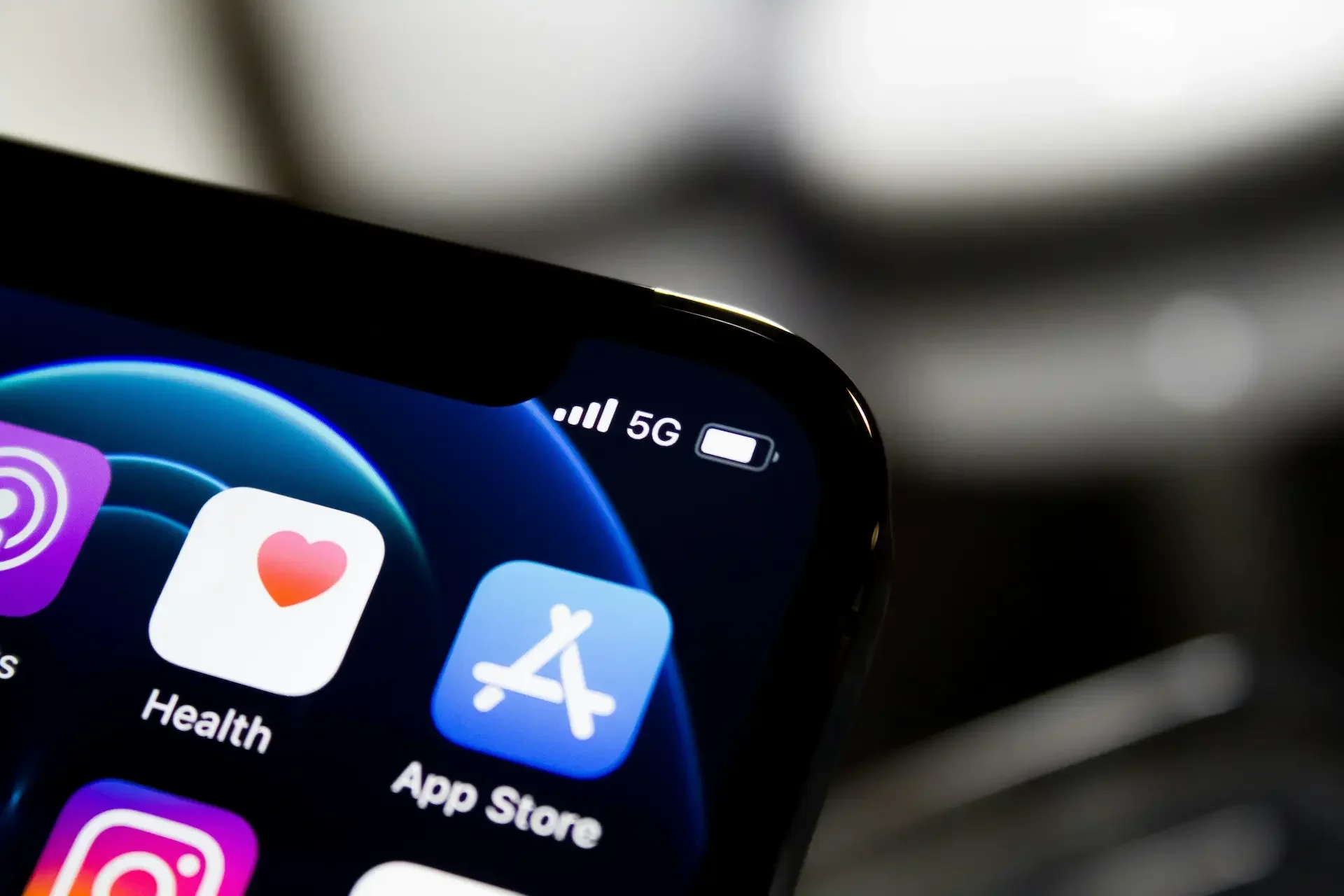 Close up of a smartphone screen showing the health and app store icons, battery level, and a 5g signal indicator—popular features on apple and google devices often monitored by the uk regulator.