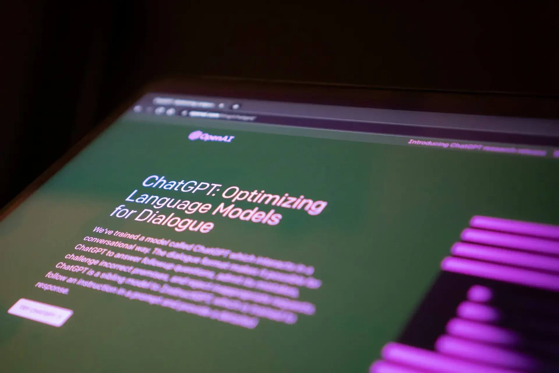 A computer screen displays the openai chatgpt homepage with the headline "chatgpt: optimizing language models for dialogue" in white and pink text on a green background, highlighting ai chat sharing features valuable to any modern marketer.