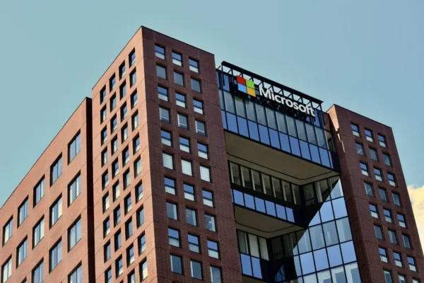 A modern office building with a red brick facade and large glass windows, featuring the microsoft logo near the top against a clear sky, showcases innovative spaces where generative ai empowers collaboration for companies like accenture.