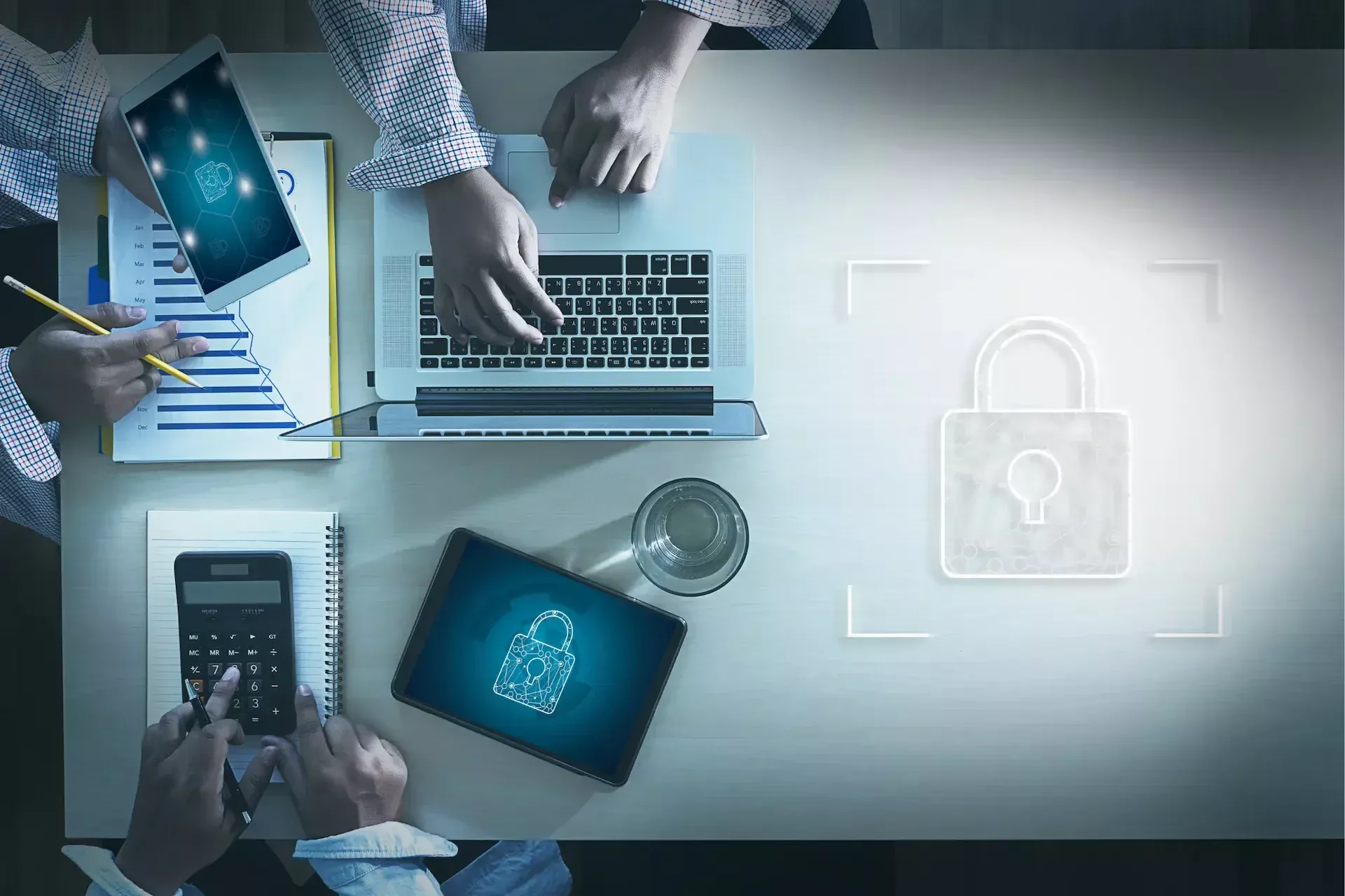 Three people work on laptops, a tablet, and a calculator at a desk, with a digital padlock graphic on the right side symbolizing secure cyber security practices.