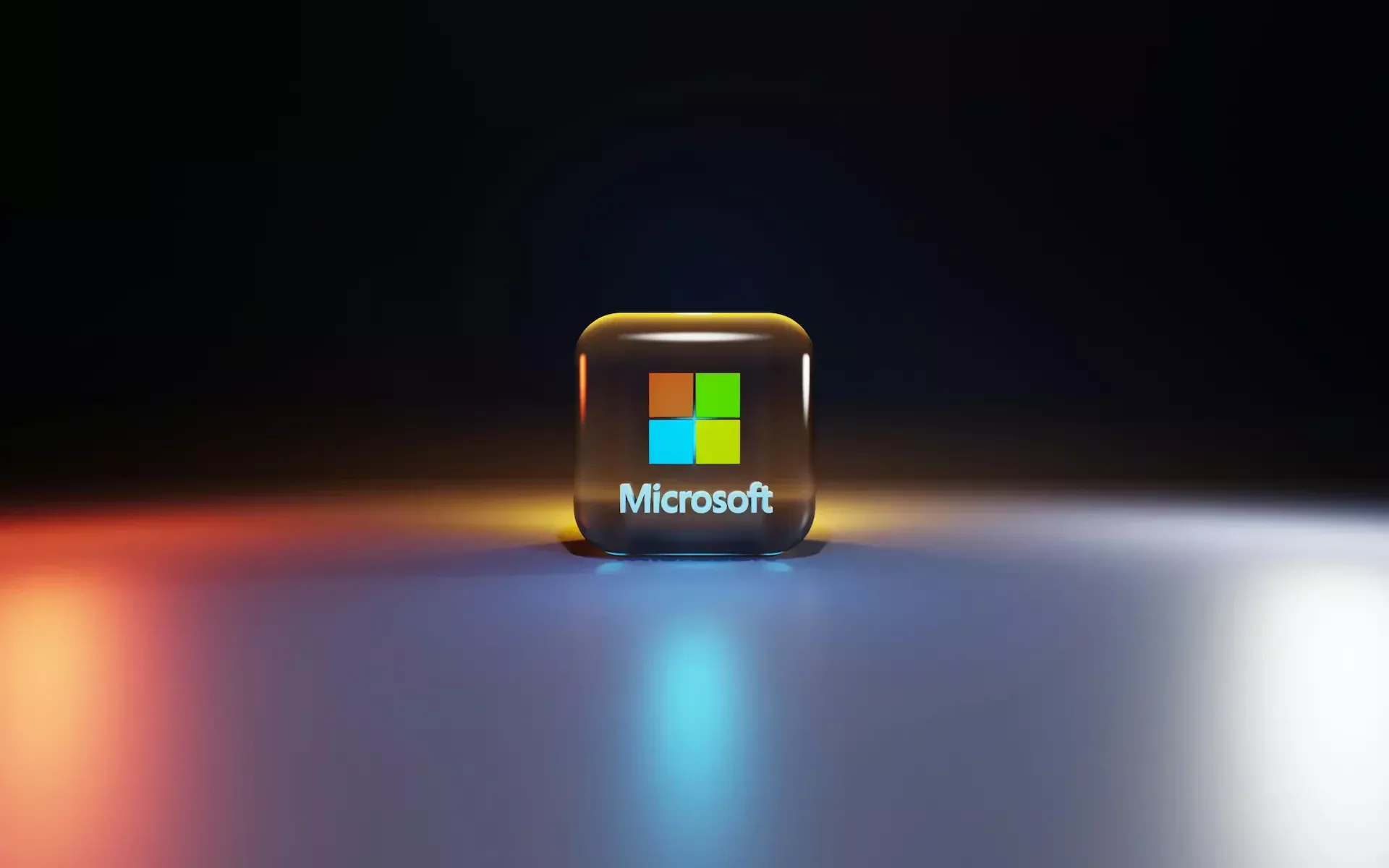 A 3d microsoft logo icon with a black background and blue, orange, and white light reflections on a glossy surface, representing microsoft 365's productivity focus and seamless ai integration.