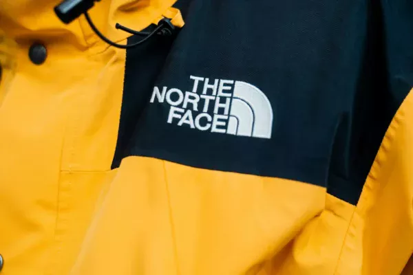 Close up of a yellow and black jacket featuring the embroidered "the north face" logo on the chest, highlighting the brand’s resilience despite recent discussions about retail cybersecurity.